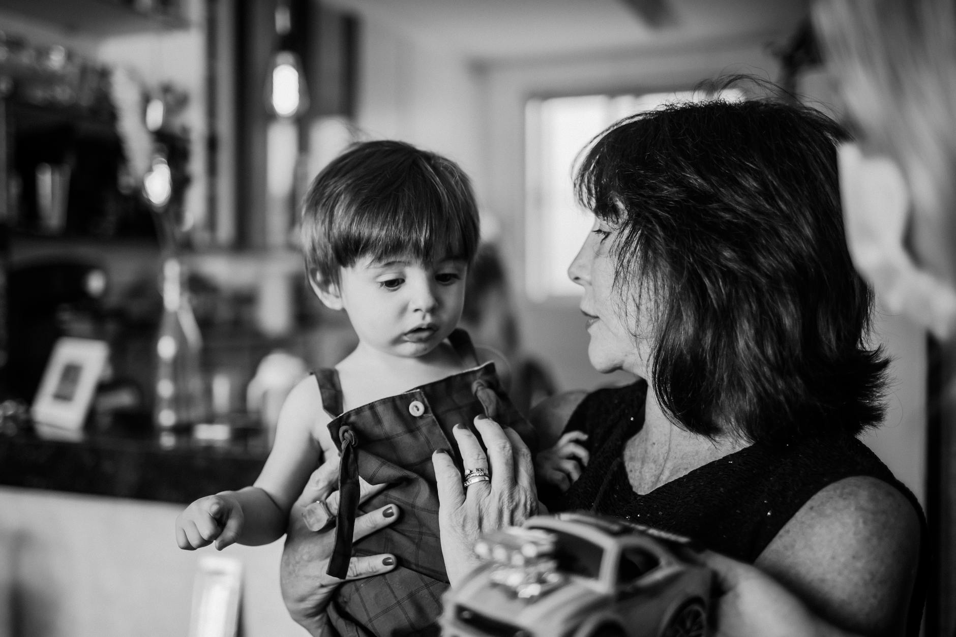Grand-mère souriante caressant un chien robot quadrupède sur le canapé, son petit-fils à côté qui tient la télécommande