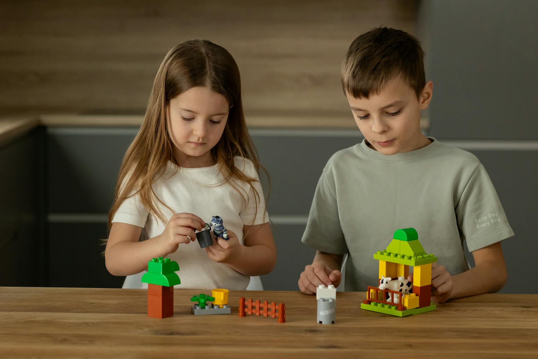 Une fille et un garçon de 8 ans qui jouent ensemble avec le même chien robot sur un tapis